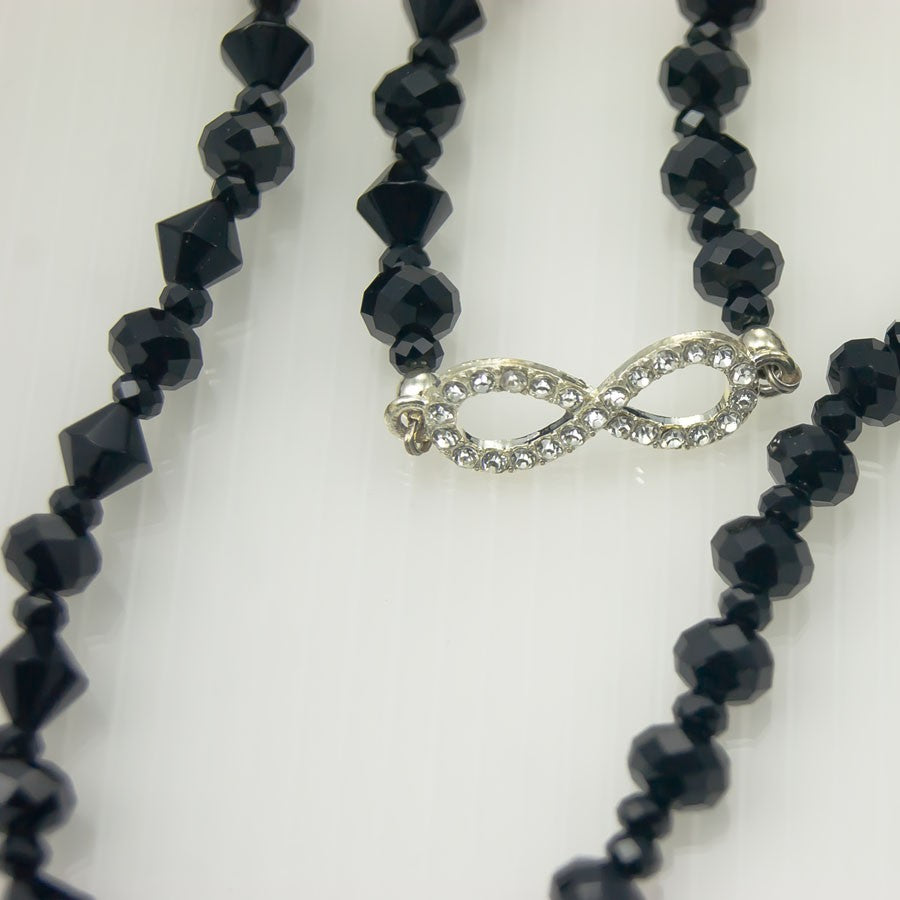 Collana LUCEOMBRA .009, unico lungo filo di cristalli neri. motivo infinito metallo e strass.