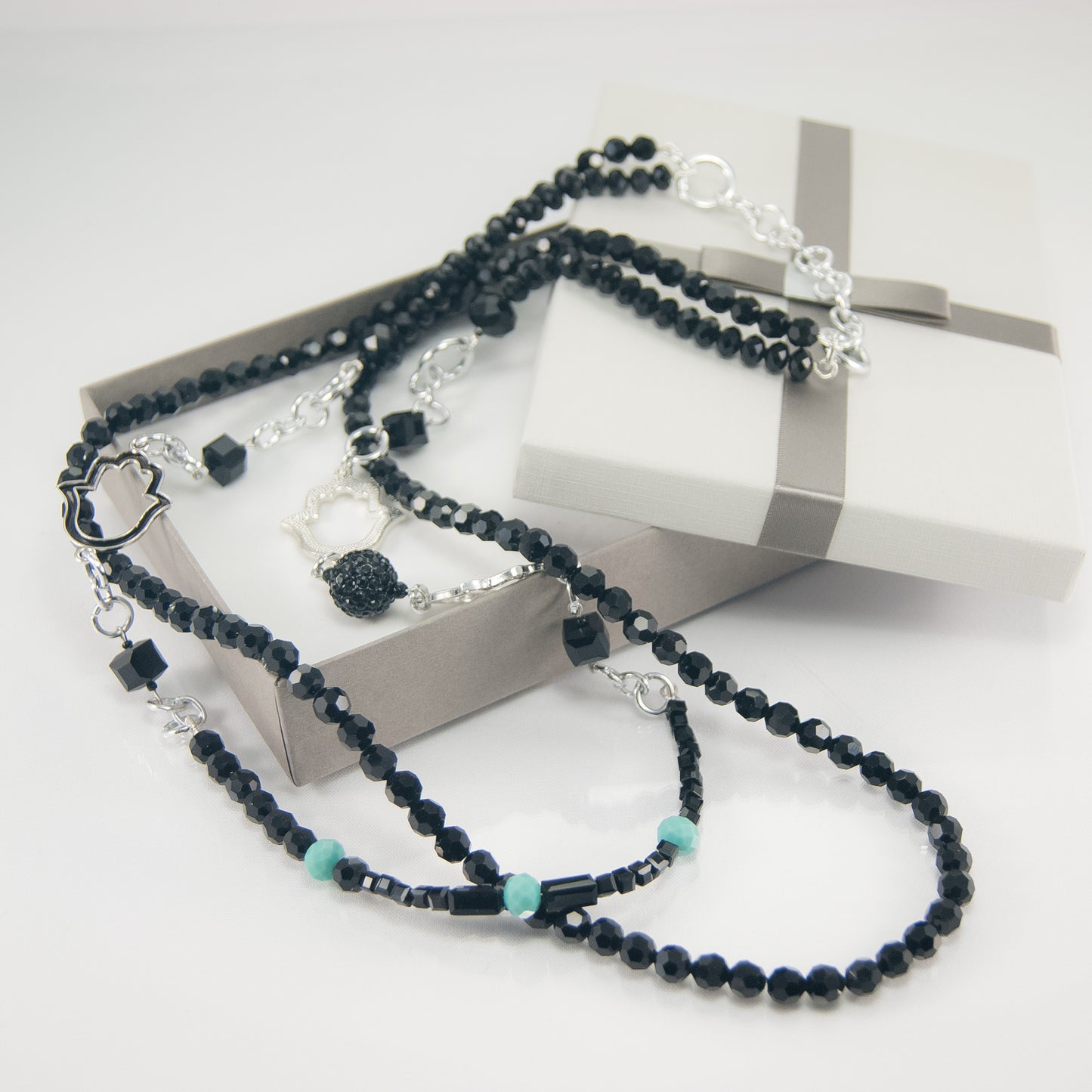 Collana I CRISTALLI .045 cristalli sfaccettati neri, perla strass e manine metalliche stilizzate.